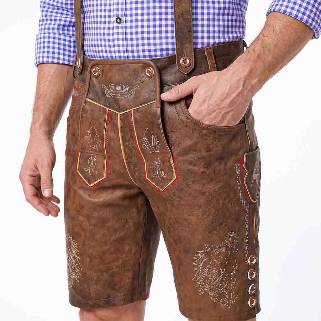Brown leather traditional Lederhosen with embroidered details, worn by a model in a blue and white check shirt against a white background.