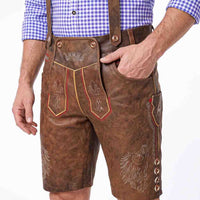 Brown leather traditional Lederhosen with embroidered details, worn by a model in a blue and white check shirt against a white background.