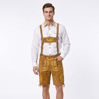 A man modeling traditional German Lederhosen, consisting of brown suede shorts with gold embroidery and suspenders, worn over a white long-sleeve shirt, against a plain white background.