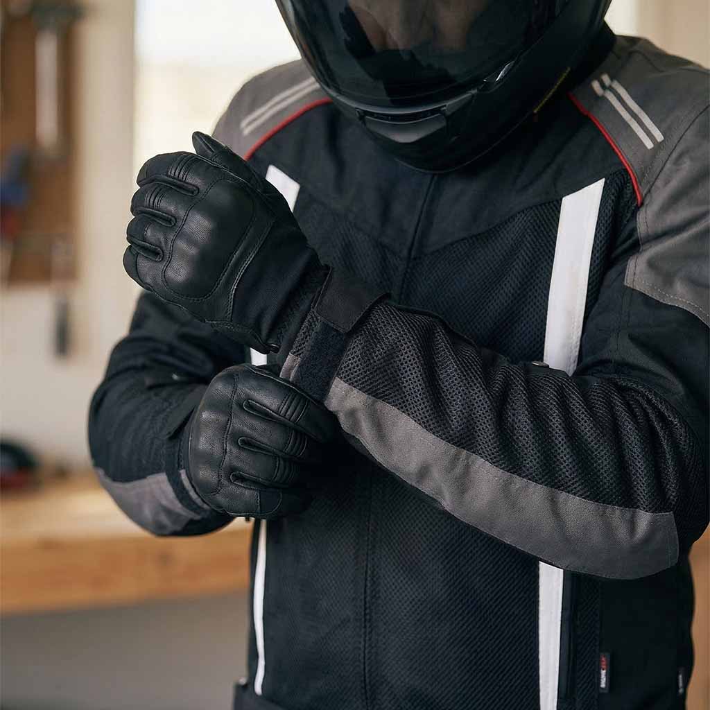 Person wearing motorcycle jacket with gloves and helmet in an indoor setting