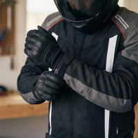Person wearing motorcycle jacket with gloves and helmet in an indoor setting