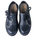 Pair of men's Oktoberfest shoes in black cowhide leather with tan embroidery, viewed from above