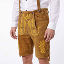 A person wearing tan suede-like traditional lederhosen shorts with yellow embroidered floral and scroll motifs, paired with a white button-up shirt, shown against a plain light background.