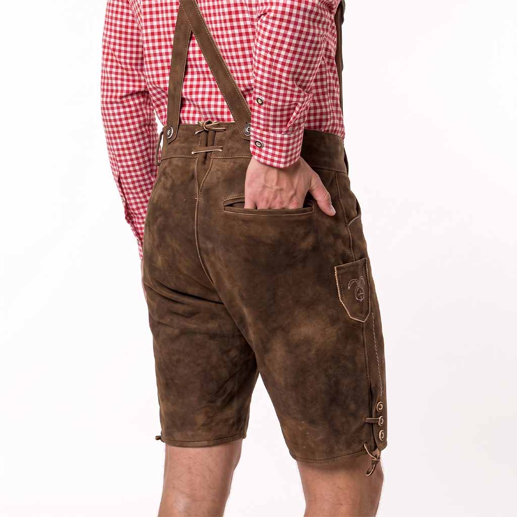 A person shown from the back wearing brown leather-like suspendered shorts with a red-and-white gingham shirt, photographed against a plain white studio background.