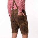 A person shown from the back wearing brown leather-like suspendered shorts with a red-and-white gingham shirt, photographed against a plain white studio background.