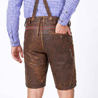 Rear view of a person wearing brown leather traditional Lederhosen with suspenders, a blue and white gingham shirt, and bare legs against a white studio background.